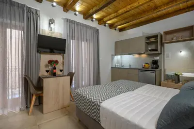 a bedroom with a bed and a desk and a kitchen at Penny's Old Town Houses in Chania Town