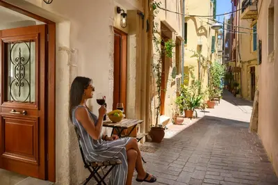 a woman sitting in a chair drinking a glass of wine at Penny's Old Town Houses in Chania Town