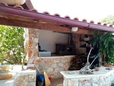 a stone patio with a table and a stone wall at apartment over the sea Private place to swim in Ravdhoúkha