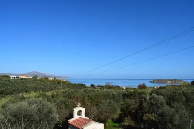 a small chapel on a hill with the ocean in the background at Elia's House Traditional & Cozy by 8essentially in Kalyves