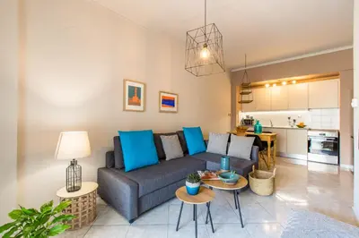 a living room with a couch and tables and a kitchen at Nautilus charm city center apt with veranda in Chania Town