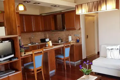 a kitchen with wooden cabinets and a living room at Double View Apartment in Agia Marina Nea Kydonias