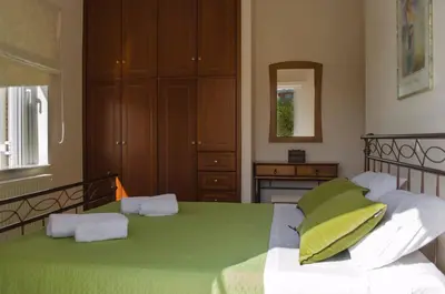 a bedroom with a bed with green sheets and a mirror at Villa Aretaki in Kalamaki Chanion