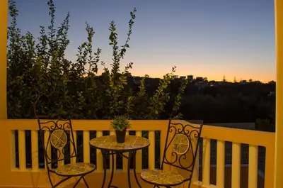 a table and chairs on a balcony with the sunset at Villa Aretaki in Kalamaki Chanion