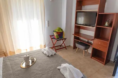 a bedroom with a bed and a tv and a chair at Camara Studios in Chania Town