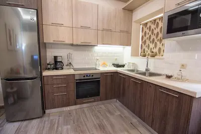 a kitchen with wooden cabinets and a stainless steel refrigerator at Pasiphae New Apartment sea & city in Chania Town