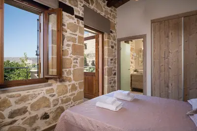 a bedroom with a stone wall and a table with towels at Doro Villas in Kissamos