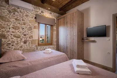a bedroom with two beds and a flat screen tv at Doro Villas in Kissamos