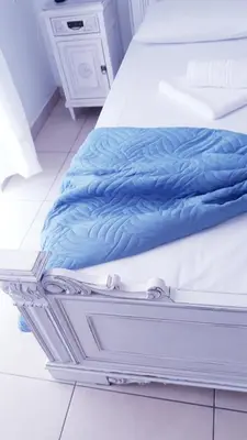 a bed with blue sheets sitting on top of it at Christos Rooms in Palaiochóra