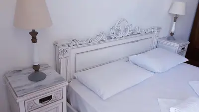 a white bedroom with two beds and two night stands at Christos Rooms in Palaiochóra