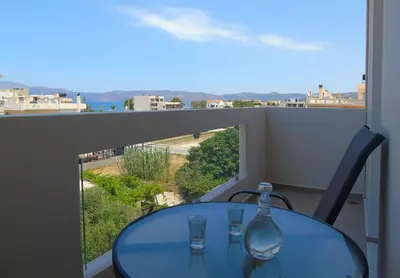 a table with two wine glasses on a balcony at Tonia's Apartment in Kissamos