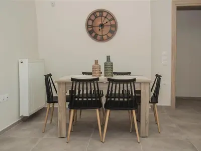 a dining room table with chairs and a clock on the wall at Tonia's Apartment in Kissamos