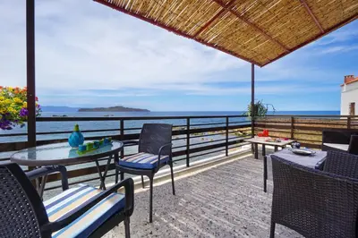 a patio with a table and chairs and the ocean at House on the sea near Chania in Galatás