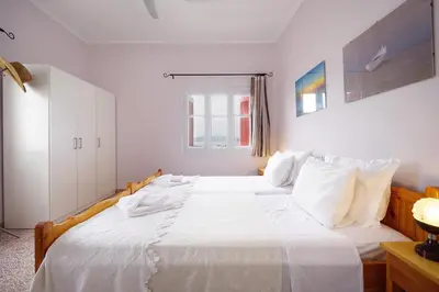 a white bedroom with two beds with white pillows at House on the sea near Chania in Galatás