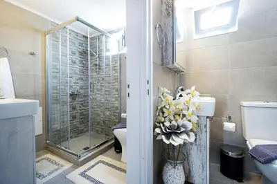 a bathroom with a shower and a toilet and a vase of flowers at House on the sea near Chania in Galatás
