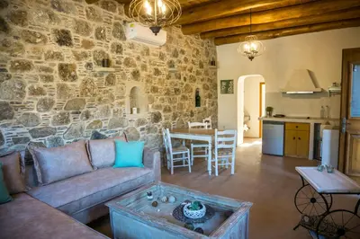 a living room with a couch and a stone wall at To Spiti mas in Sougia