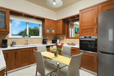 a kitchen with wooden cabinets and a table with flowers on it at Cedar Tree Villa in Kounoupidhianá