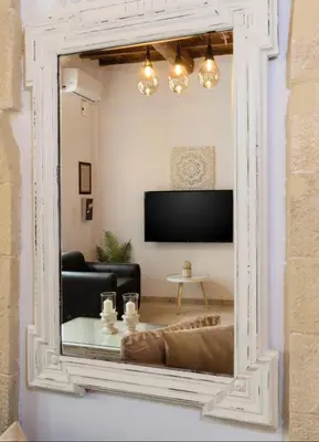 a mirror reflecting a living room with a couch and a tv at Diogenis Residence Euphoria in Arménoi