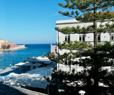 a large white building with a tree in front of the water at Old Port - Bellavista Studio in Chania Town