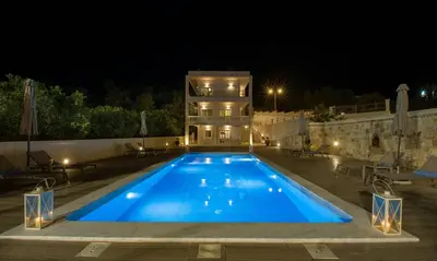 a swimming pool in front of a house at night at Queen Electra with pool and tennis court in Alikianós