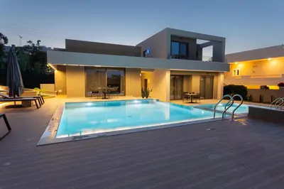 a house with a swimming pool in front of a house at Twins Apartments in Plataniás