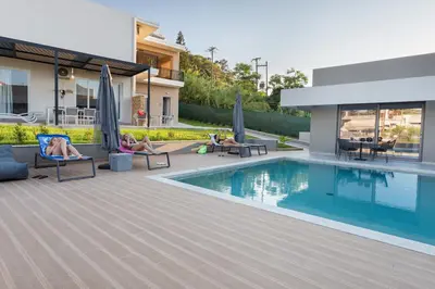 a group of people sitting in chairs by a swimming pool at Twins Apartments in Plataniás
