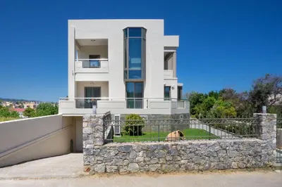 a large white house with a stone wall at Alexandra Apartment in Daratso