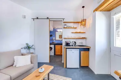 a living room with a couch and a kitchen at Skiff - Transformed studio on the water's edge in Chania Town