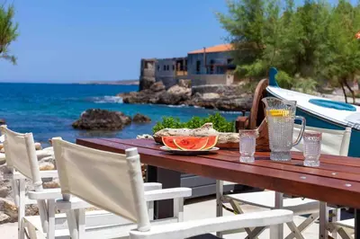 a wooden table with a plate of food on the beach at Skiff - Transformed studio on the water's edge in Chania Town