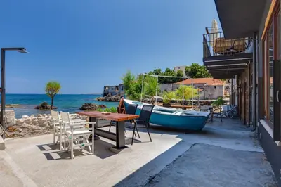 a table and chairs and a boat on a patio at Skiff - Transformed studio on the water's edge in Chania Town