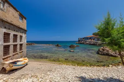 a boat sitting on the beach next to a building at Skiff - Transformed studio on the water's edge in Chania Town