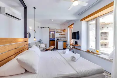 a bedroom with a large white bed in a room at Skiff - Transformed studio on the water's edge in Chania Town