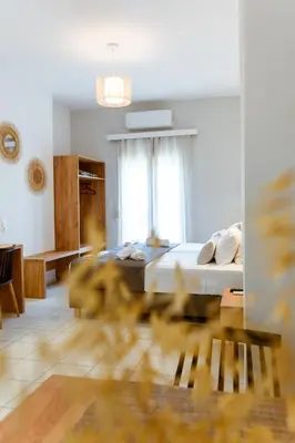 a white bedroom with a bed and a window at Koulouris Apartments & Studios in Kalyves