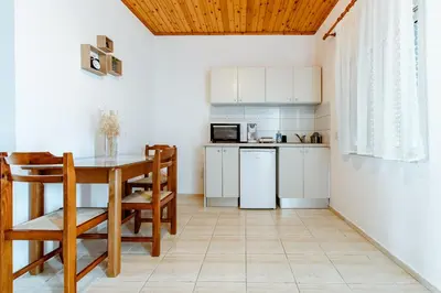 a small kitchen with a table and a refrigerator at Koulouris Apartments & Studios in Kalyves