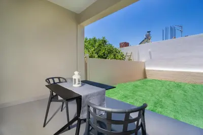 a patio with a table and chairs and green grass at Ariadne Apartment in Daratso