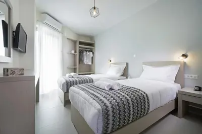 a bedroom with two beds with white sheets and a tv at Ariadne Apartment in Daratso