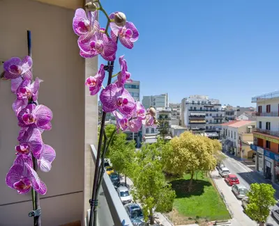 a view of a city from a balcony with purple flowers at M City Hotel in Chania Town