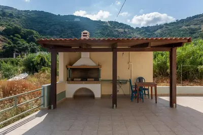 a covered patio with a grill and a table at House just on the beach -included 2 canoe and 2 bicycles in Ravdhoúkha