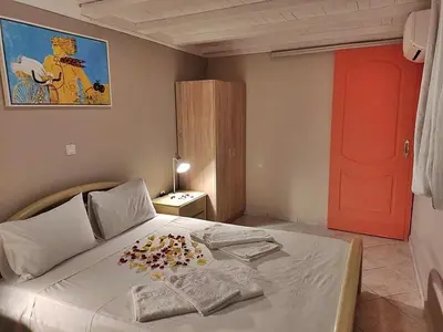 a bedroom with a white bed with a red door at House just on the beach -included 2 canoe and 2 bicycles in Ravdhoúkha
