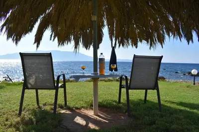two chairs and a table under an umbrella at the beach at House just on the beach -included 2 canoe and 2 bicycles in Ravdhoúkha