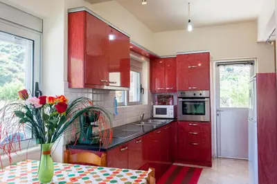a kitchen with red cabinets and a vase of flowers on a table at House just on the beach -included 2 canoe and 2 bicycles in Ravdhoúkha