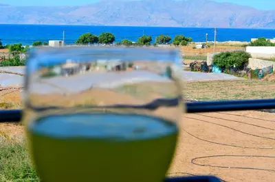 a glass of wine sitting on top of a table at Balos Residence private pool Seafront Seaview in Kissamos