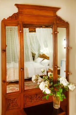 a wooden cabinet with a mirror on a table with flowers at Palazzo di Pietro in Chania Town