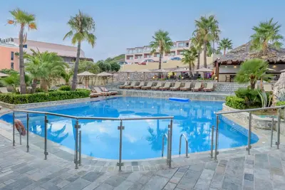a swimming pool at a resort with palm trees at Eurohotel Theo Hotel in Agia Marina Nea Kydonias