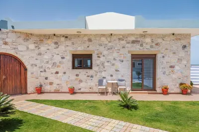 a stone building with a patio with a table and chairs at Dream Sea House villa Falassarna in Falasarna
