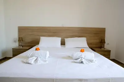 a large white bed with two orange pillows on it at Lefka Ori in Khóra Sfakíon