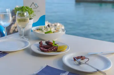 a table with two plates of food and a glass of wine at Lefka Ori in Khóra Sfakíon