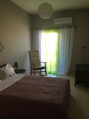 a bedroom with a bed and a chair and a window at 180 Degree Sea View Apartment in Palaiochóra