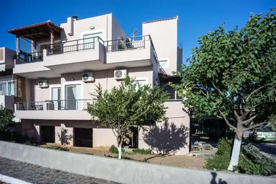 a white building with trees in front of it at 180 Degree Sea View Apartment in Palaiochóra