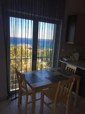 a table and chairs in a kitchen with a view of the ocean at 180 Degree Sea View Apartment in Palaiochóra